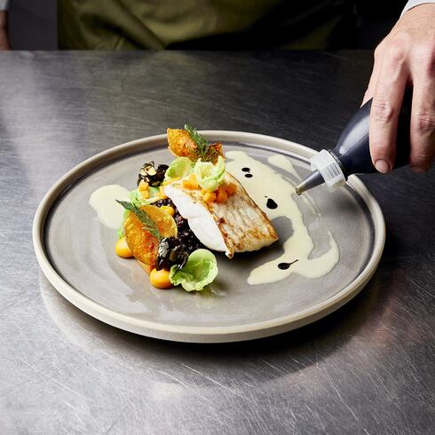 Anrichten eines Fischgerichts mit Soße