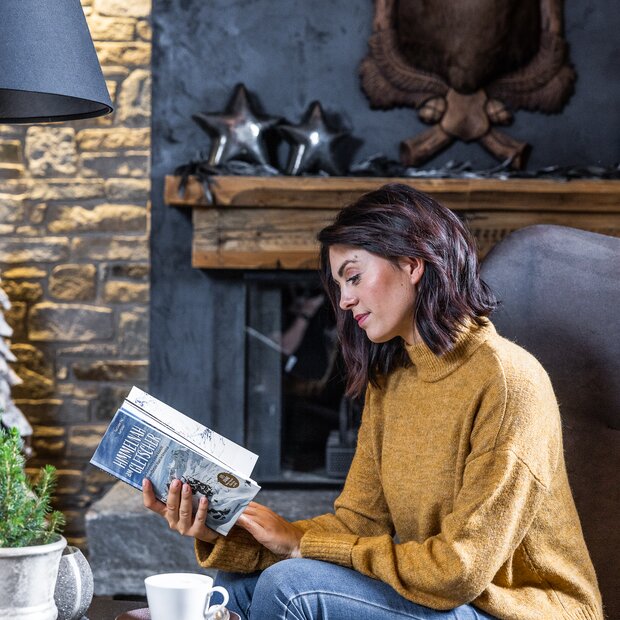 Junge Frau liest Buch in gemütlicher Lounge