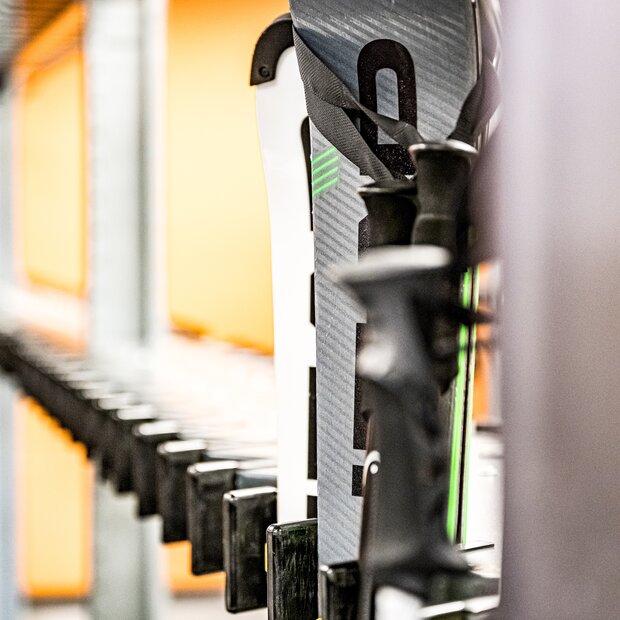 Aufgereihte Skier und Skistöcke im Skiregal