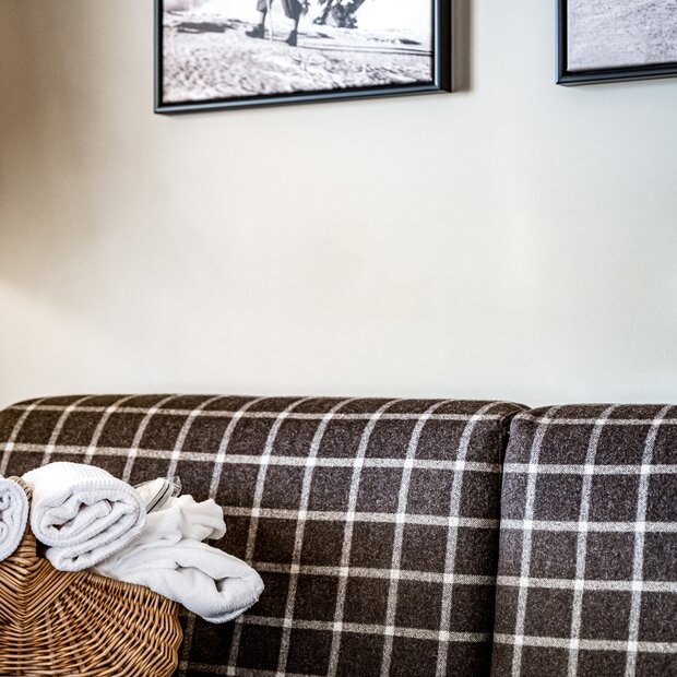 Checkered sofa with a towel basket under a mountaineering picture