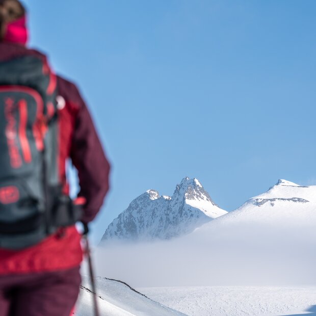 Ski tourer with backpack in front of snow-covered mountain landscape
