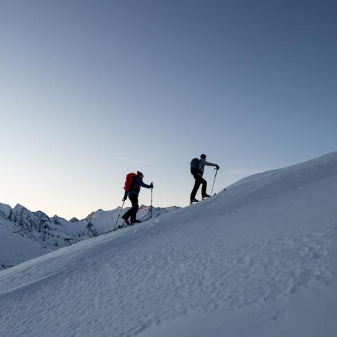 Two ski tourers on a snow-covered mountain slope